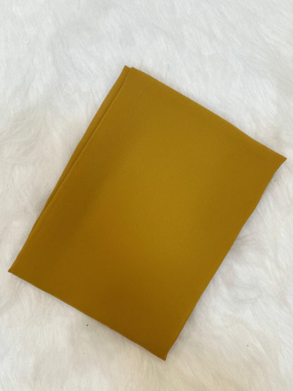 Chiffon fabric in mustard yellow, folded to reveal texture and finish.