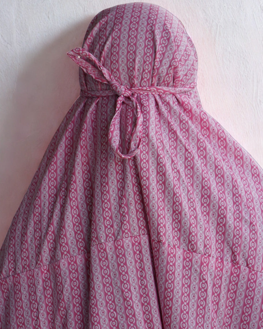 Back view of pink patterned prayer dress with adjustable tie for secure fit.