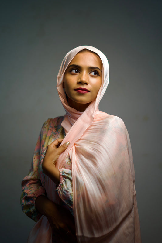 Woman wearing a rose gold hijab with light shimmer and smooth folds.