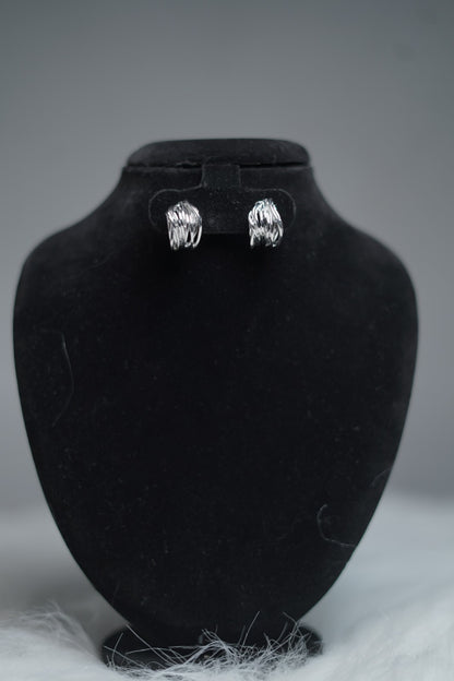 Sculpted silver hoops displayed on earring stand.