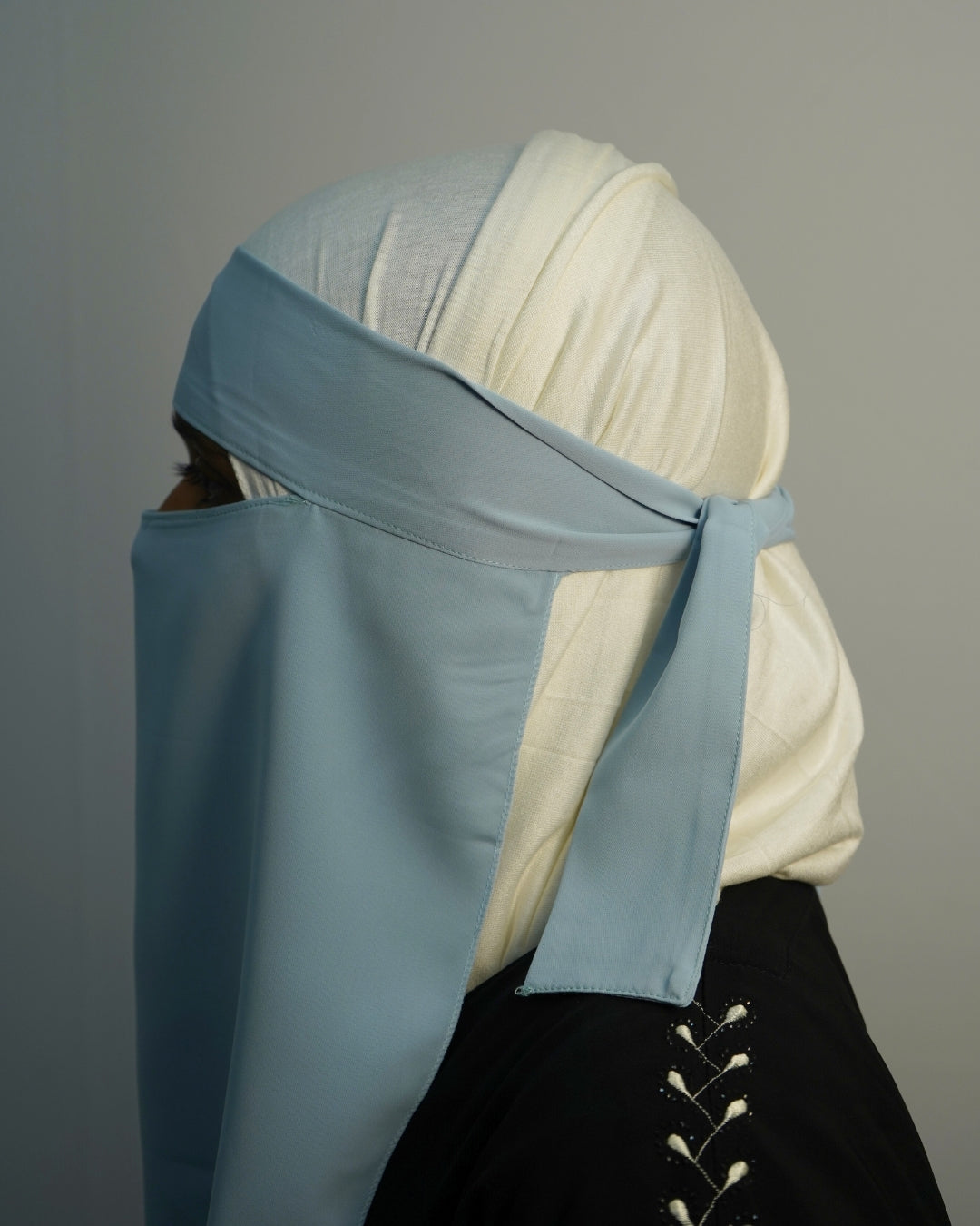 Side view of sky blue niqab tied at the back.
