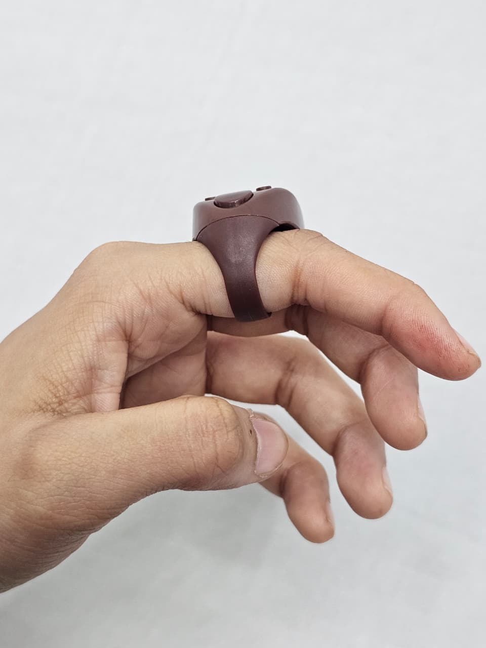 Side view of brown plastic dhikr counter showing strap design.