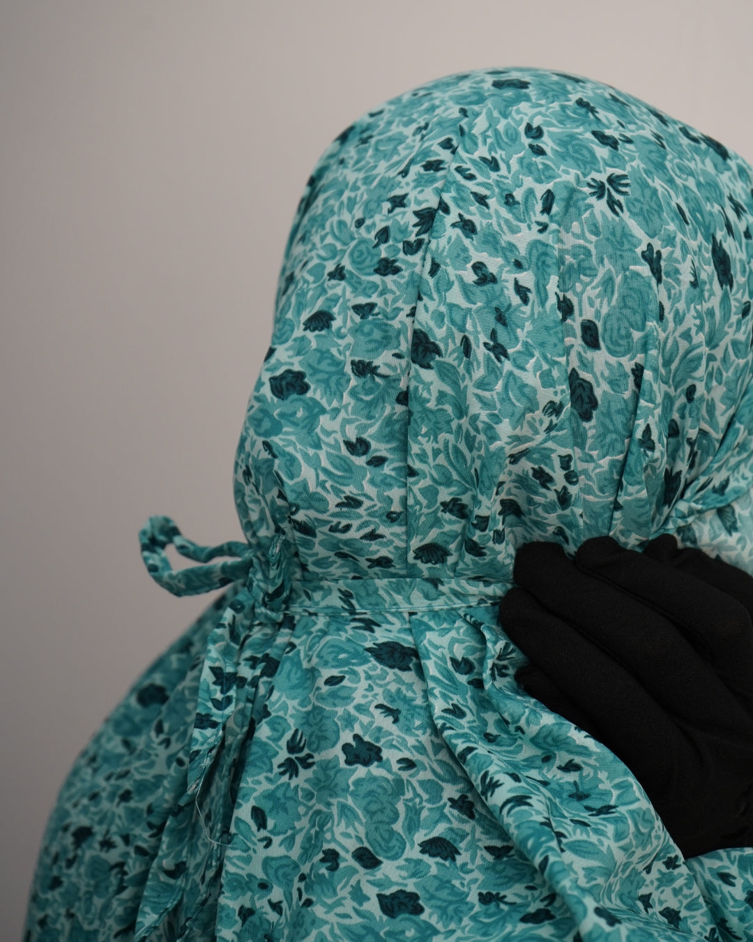 Close-up of tie-back headscarf in teal green floral design.