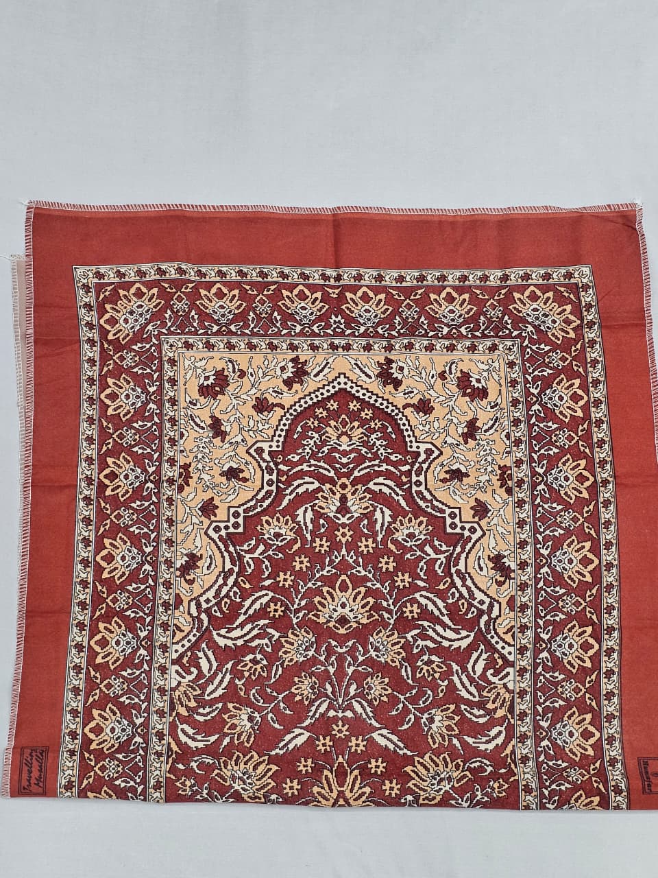 Portable maroon Islamic prayer mat with traditional design.