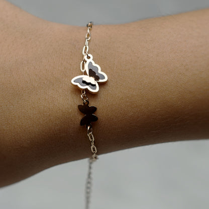 Close-up of butterfly bracelet with enamel charms, shown on model’s wrist.