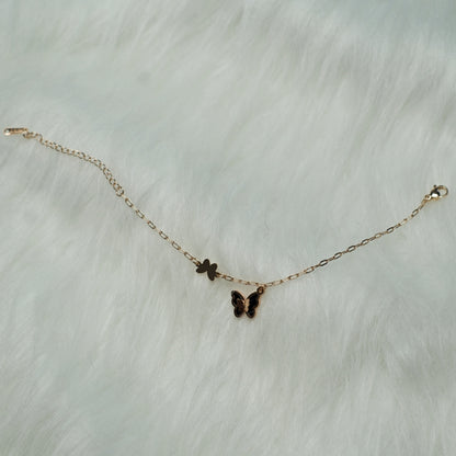Twin butterfly charm bracelet resting on fuzzy textured background.