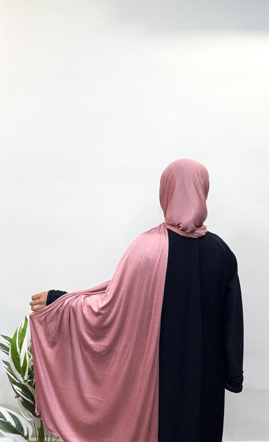 Woman in watermelon pink jersey hijab with smooth texture.