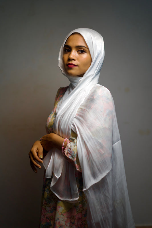 White shimmer scarf worn in a front wrap, glowing under soft light.