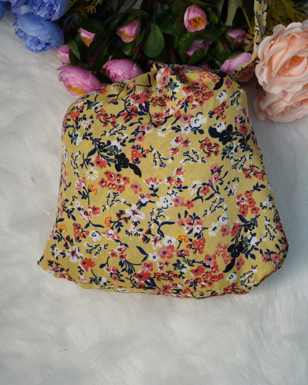 Compact matching fabric pouch in yellow floral print, placed on a soft white surface.